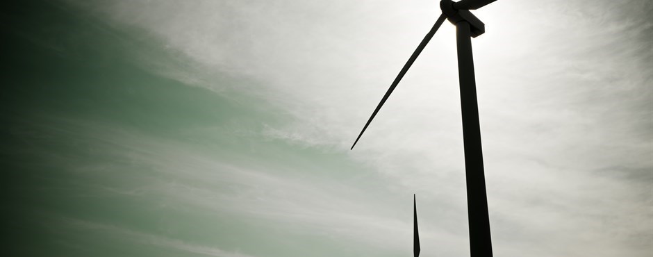 The photo shows a wind turbine with focus on the rotor and blades